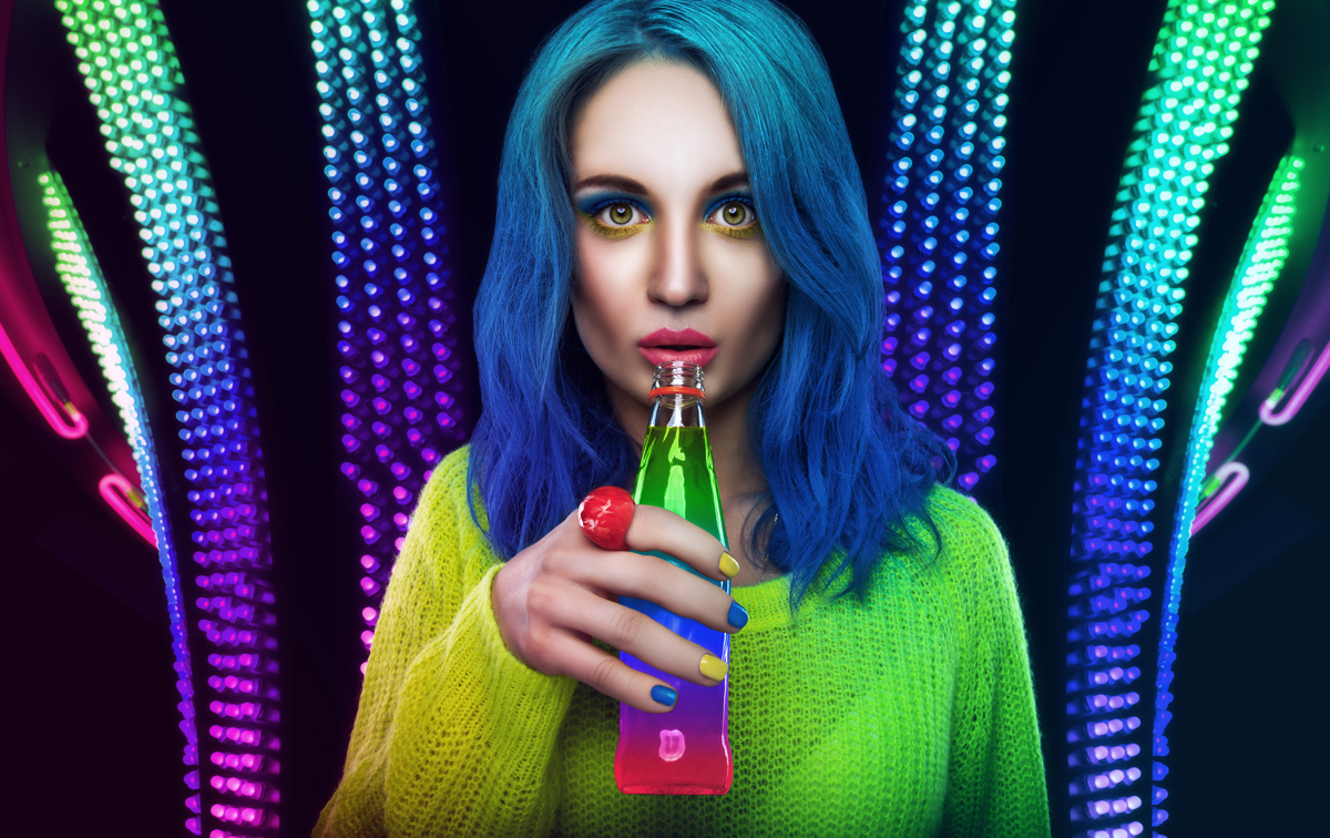 Bright girl with blue hairs is drinking cocktail